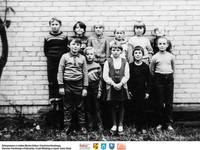 Dzieci stoją przy ścianie  **Children standing by the wall - b159<br />Dofinansowano ze środków Ministra Kultury i Dziedzictwa Narodowego, Starostwa Powiatowego w Białymstoku, Urzędu Miejskiego w Łapach, Gminy Sokoły<br />